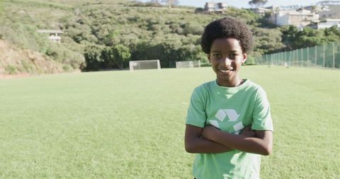 Confident Boy on Soccer Field with Recycling Shirt and Cheerful Smile