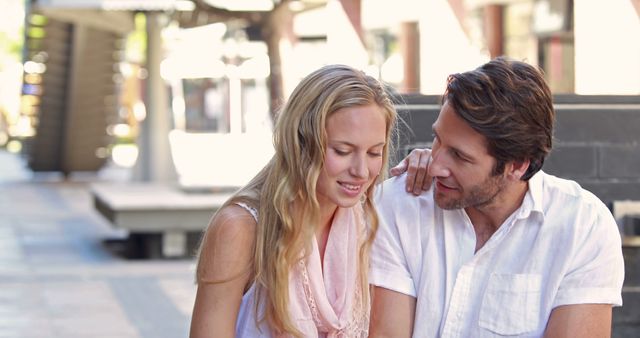 A Caucasian couple, in their young adult years, shares an intimate moment on a city street, with copy space. Their close proximity and affectionate body language suggest a romantic connection.