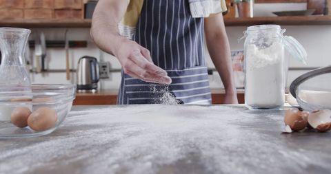 Man Preparing to Bake by Sprinkling Flour in Rustic Kitchen