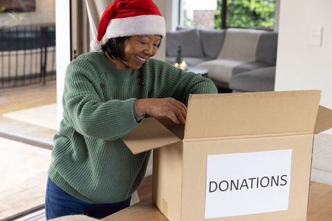 Senior Woman in Santa Hat Opening Charity Donations Box at Home