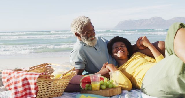Happy african american couple having picnic on sunny beach. healthy and active time beach holiday.
