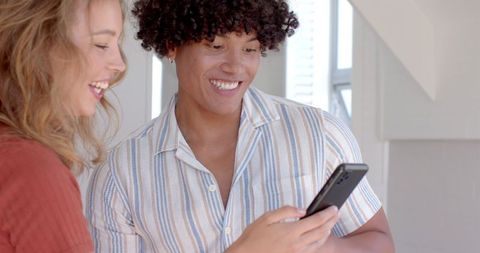 Diverse Friends Smiling and Browsing Smartphone in Bright Kitchen