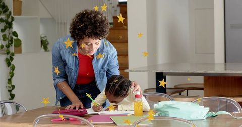Caregiver guiding child doing homework at kitchen table during homeschooling and tutoring
