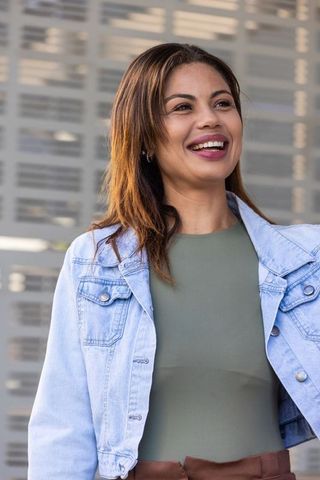 Confident african american woman smiling outdoors in denim jacket by modern facade