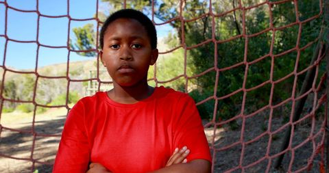 Confident boy in red shirt posing by soccer goal