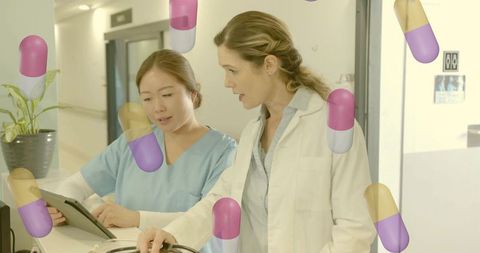 Doctor and nurse discussing patient care using tablet with floating capsule graphics