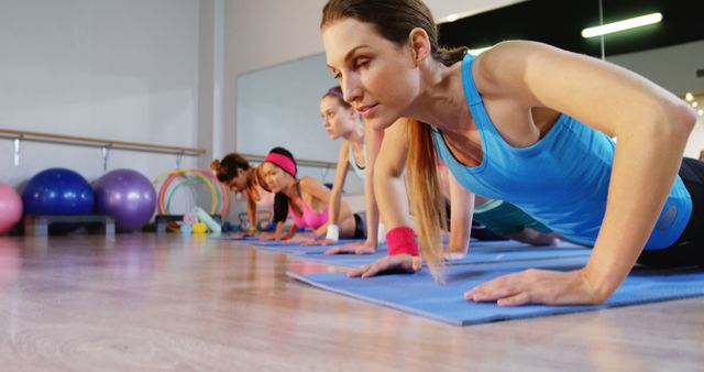 A group of diverse women engage in a fitness class, practicing yoga or pilates on mats, with copy space. Their focus and determination reflect a commitment to health and wellness.