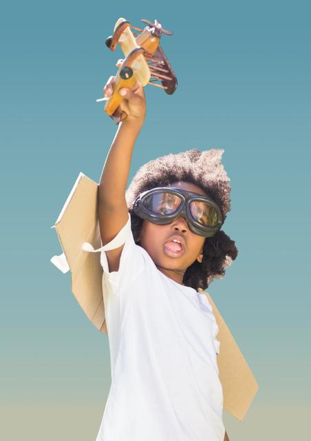 Close-up of superhero kid in flying goggles playing with toy aeroplane