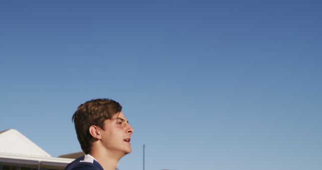 Young Man in Sporty Outfit Jogging Outdoors Against Clear Blue Sky - Download Free Stock Images Pikwizard.com