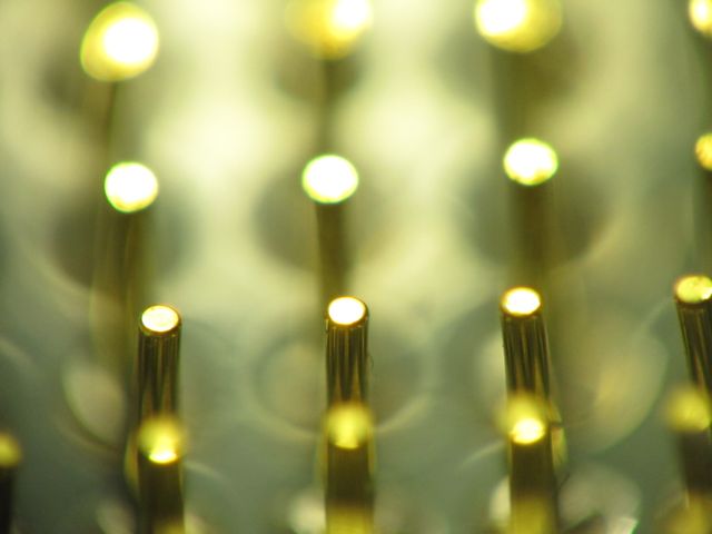 Image showcases a blurred close-up view of gold electronic pins on a circuit board, highlighting the intricate details and precision engineering. Ideal for use in technology-related content, electronics websites, or as a background for presentations and marketing materials in the tech industry.