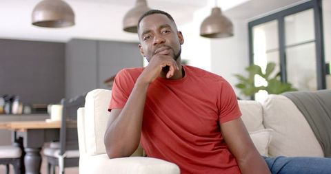Thoughtful Man in Red Shirt Relaxing at Home