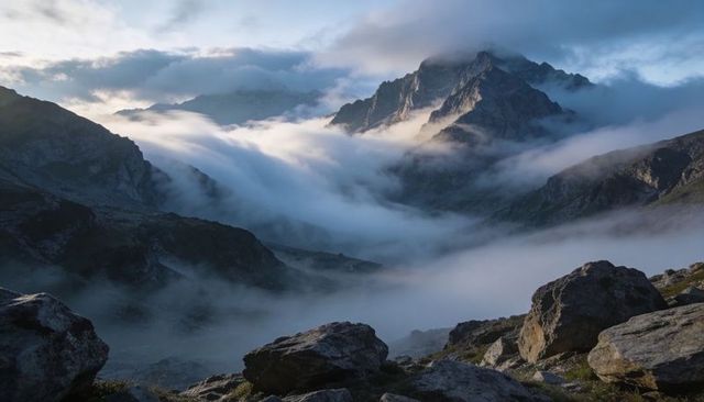 Rolling cloud waterfall filling alpine valley around jagged mountain peak at dawn