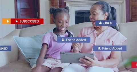 Smiling grandma and granddaughter exploring tablet with social media tags and headphones