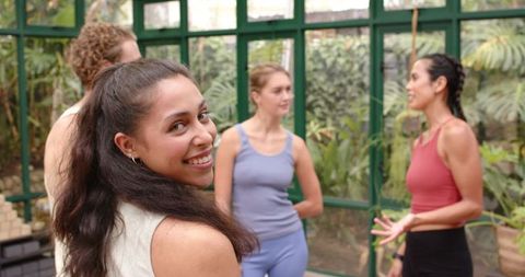 Women in Yoga Attire Enjoying Group Conversation In Greenhouse