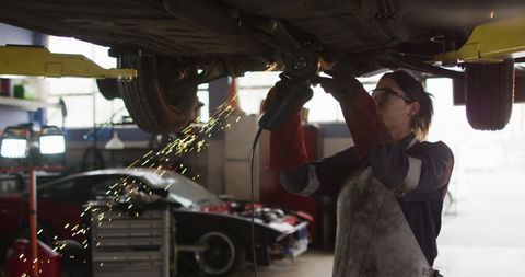 Mechanic using grinder on vehicle in automotive workshop