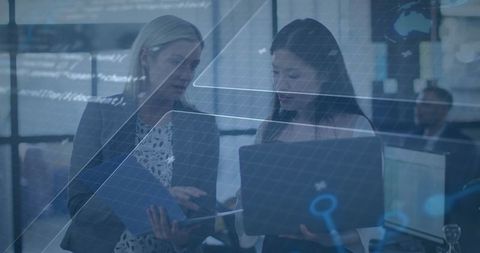 Businesswomen Analyzing Data on Laptop with Digital Graphics Overlay