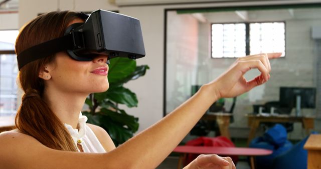 The business executive appears to be engaged with virtual reality technology in an office environment, embodying a modern workplace scenario. This image can be ideal for business-related articles, blogs, or presentations discussing future tech, innovation in the workplace, and virtual reality applications in business. It is also suitable for marketing and promotional materials focused on corporate technology solutions.