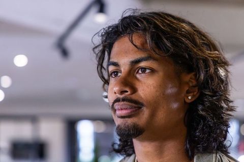 Contemplative indian man mid twenties headshot with stud earring and soft bokeh