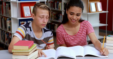 Teens collaborating in library for study session amidst books