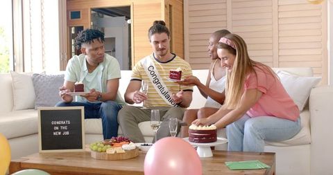 New job celebration with group of diverse friends in cozy living room