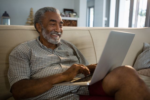Senior man using laptop in the living room at home