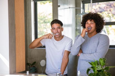 Happy Friends Brushing Teeth in Modern Bathroom