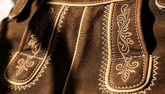 Displaying brown suede lederhosen panel with embroidered straps and zigzag stitching detail