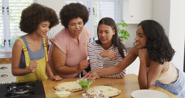 Happy diverse female friends talking and cooking together in kitchen. spending quality time at home.
