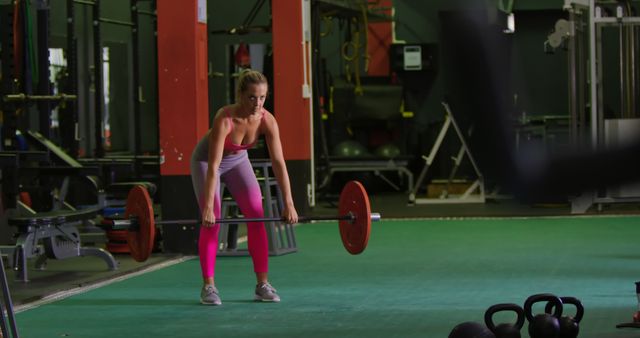 Caucasian woman lifting weights at the gym. Her workout routine emphasizes strength training and fitness discipline.