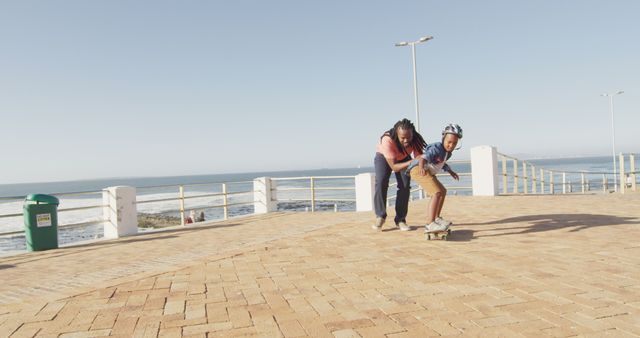 Father teaching young son how to skateboard near seaside - Download Free Stock Images Pikwizard.com