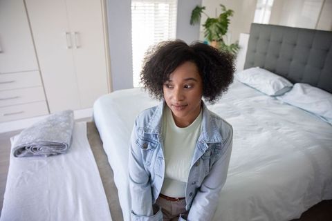 Thoughtful woman in denim jacket in modern bedroom