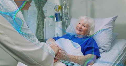 Elderly woman receiving compassionate hospital care holding nurse hand beside iv drip