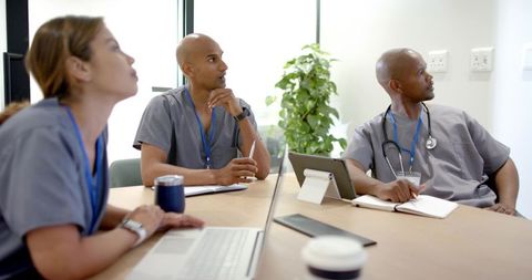 African american medical team collaborating during clinic meeting with laptop and tablet