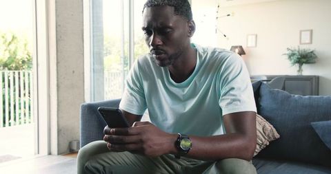 Casually Relaxed Man Engaged with Smartphone in Modern Living Room