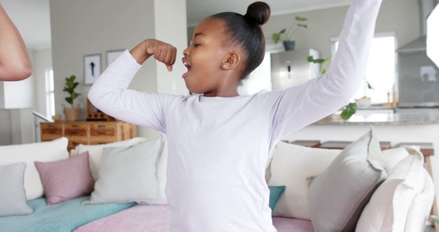 Excited African American Girl Flexing Muscles in Living Room - Download Free Stock Images Pikwizard.com