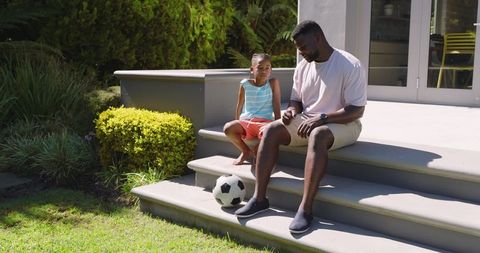 Father and Son Sitting on Steps - Tranquil Moment Bonding with Soccer Ball