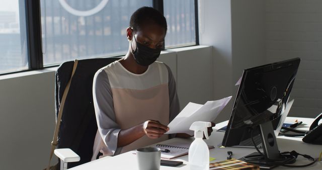 African American Businesswoman in Mask Reading Documents at Desk - Download Free Stock Images Pikwizard.com