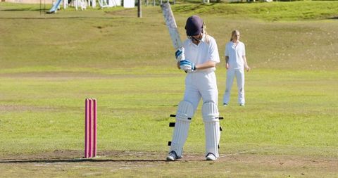 Female cricketer preparing to bat on lush field