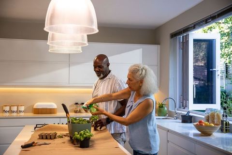Senior couple engaged in herb gardening together at modern kitchen