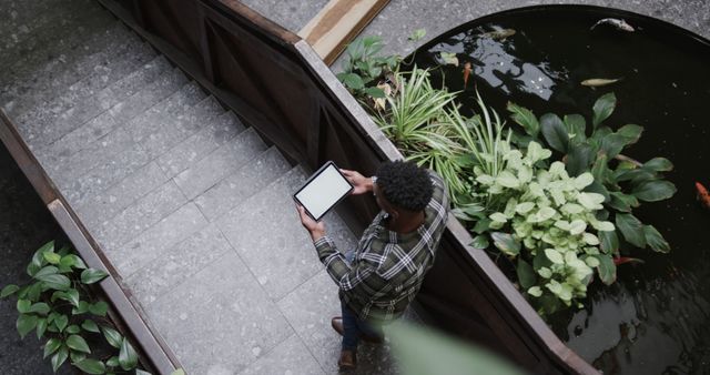 Person Holding Tablet Walking Past Indoor Pond with Koi Fish - Download Free Stock Images Pikwizard.com