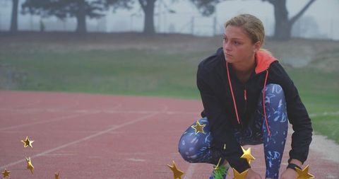 Teenage female sprinter adjusting laces on track preparing for race focused determination