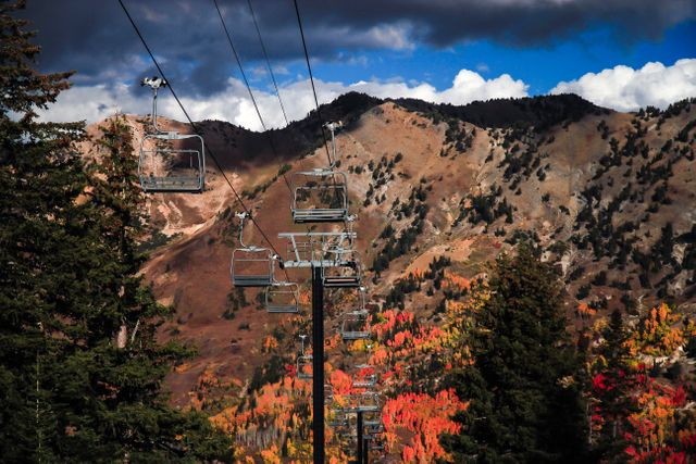 Mountain ski lift running through a vibrant autumn landscape with hills and colorful trees. Ideal for travel brochures, tourism advertisements, and inspirational outdoor photography collections.