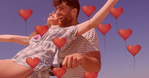 Couple riding bicycle with heart balloons on sunny beach romantic summer love ride