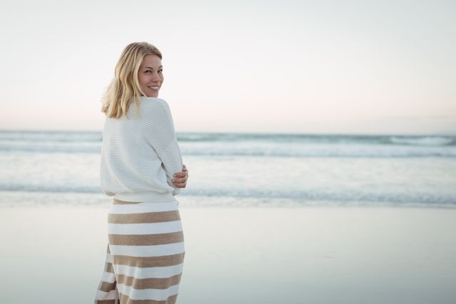 portrait of smiling woman standing at beach during dusk