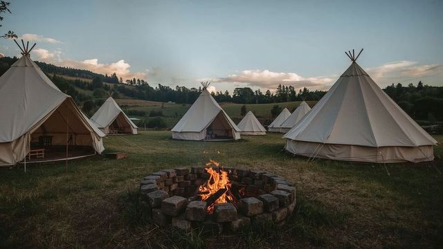 Idyllic Bell Tent Camping Site with Glowing Fire Pit at Dusk