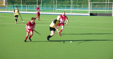 Competitive field hockey match on synthetic turf during sunny day