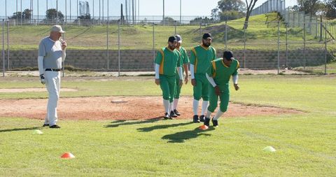 Asian Male Baseball Players Practicing Pitcher Drill With Senior Coach on Sunny Field