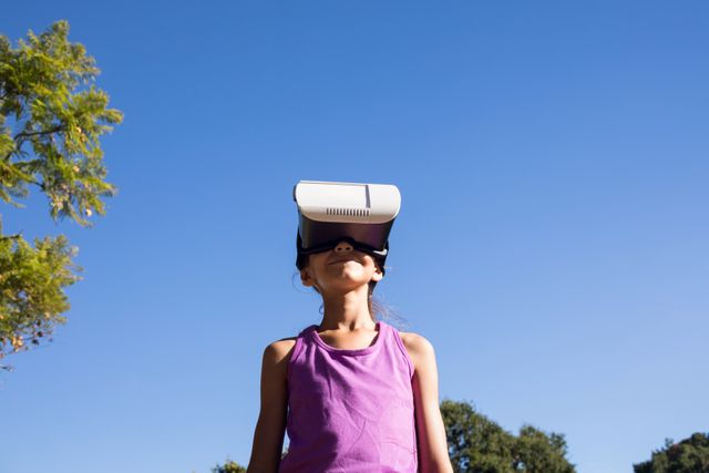 Playful girl using vr headset in the park