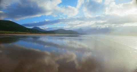 Transparent reflections on beach with dramatic cloudy sky