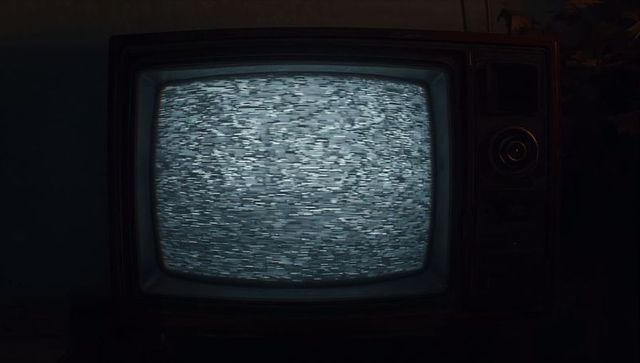 Vintage CRT Television Displaying White Noise in Dim Room